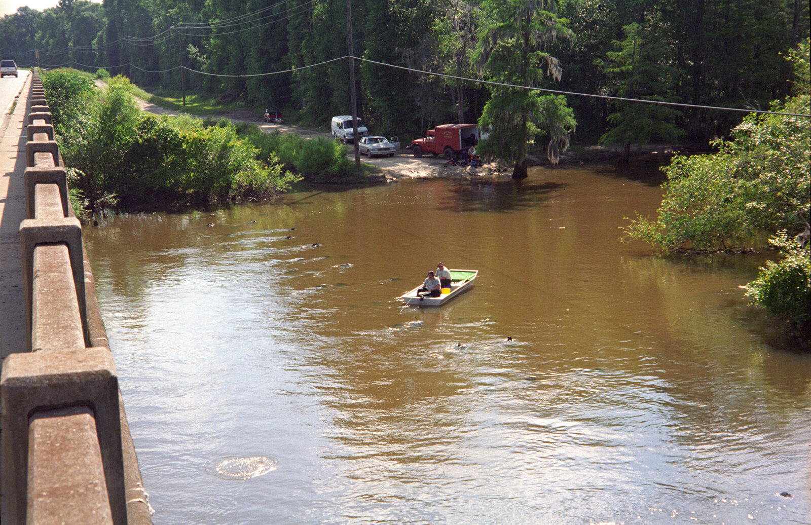 Divers searching a river below a bridge while two team members watch from a small boat
